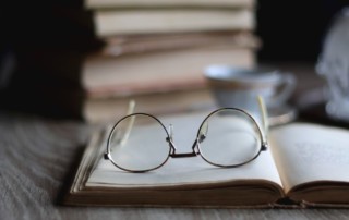 stack of books with reading glasses on top; the difference between contemporary fiction and literary fiction