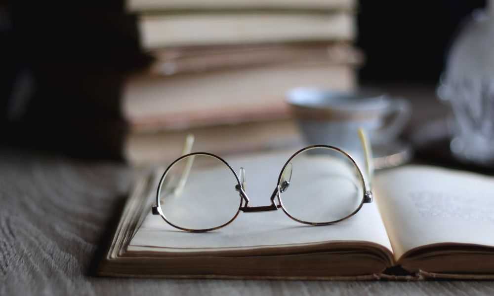 stack of books with reading glasses on top; the difference between contemporary fiction and literary fiction