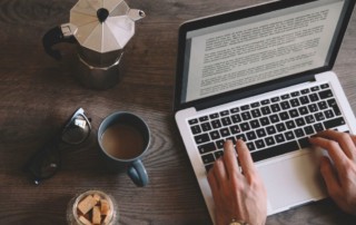 man editing a Word file on a laptop with a coffee cup on the table; what does a book editor do