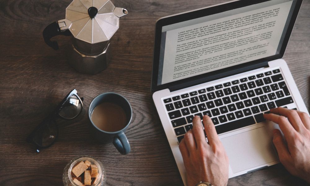 man editing a Word file on a laptop with a coffee cup on the table; what does a book editor do