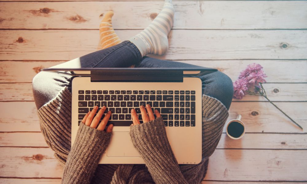 woman sitting on floor typing on a laptop; 9 steps to write a book