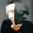 man in black shirt holding a mask that's half white and half black; what is a trope?